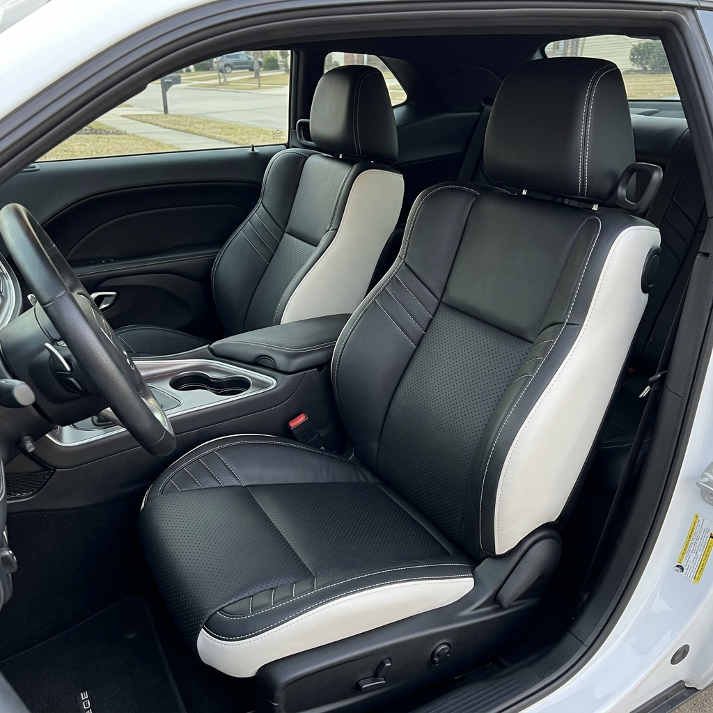Front in-cabin view of a 2015–2023 Dodge Challenger Hellcat with Leatherteck seat covers installed, featuring Pearl White outer panels, black front-facing seat panels, perforated combination inserts, black accent panels, and Pearl White contrast stitching, shown from the open driver-side door with the front bucket seats, headrests, steering wheel, center console, cupholders, door panel, and rear seat area visible.